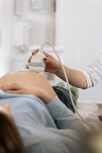 A pregnant woman undergoing a medical ultrasound in a clinical setting.